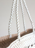 Close-up of hand-woven genuine leather tote bag with braided white handles