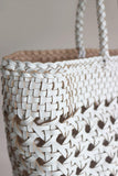 Close-up of a hand-woven genuine leather tote bag with braided handles and open weave design