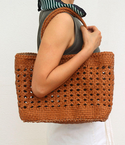 Woman holding a hand-woven genuine leather tote bag with a cuboid shape and braided handles
