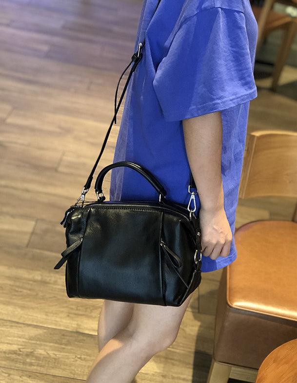 Woman carrying a black genuine leather handbag with shoulder strap indoors