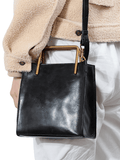 Woman carrying a black genuine cowhide leather shoulder bag with gold metal handle