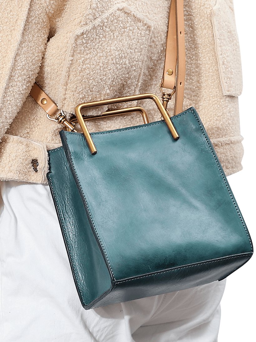 Teal genuine leather shoulder bag with gold-tone handle and tan strap, worn crossbody