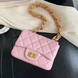 Pink quilted leather shoulder bag with gold chain strap and clasp on black and cream fabric