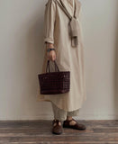 Woman in neutral outfit holding a handwoven genuine leather cuboid tote bag