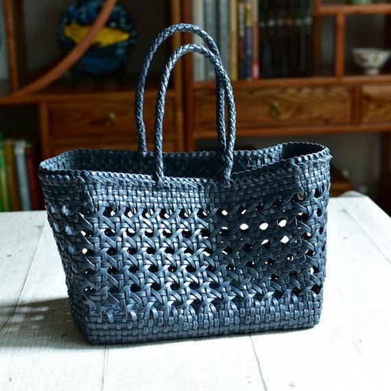 Handwoven genuine leather tote bag with cuboid shape and woven rattan pattern on table.