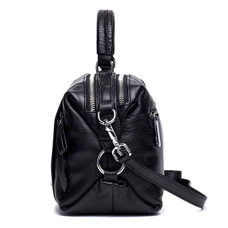 Black genuine leather handbag with silver zippers and detachable strap, side view