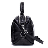 Black genuine leather handbag with silver zippers and detachable strap, side view