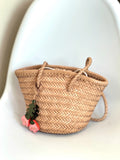 Hand-woven cowhide leather bucket bag with braided drawstring and leaf charm on white chair
