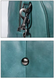 Close-up of teal full grain leather duffle bag with metal zipper, clasp, and button details