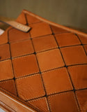 Handcrafted brown cowhide leather handbag with woven square pattern and visible stitching