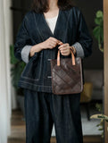Woman holding a brown quilted cowhide leather handbag with tan handles, casual indoor setting