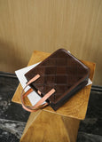Handcrafted brown cowhide leather handbag with tan handles on a wooden table