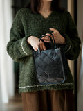 Woman holding black handcrafted cowhide leather handbag with quilted pattern