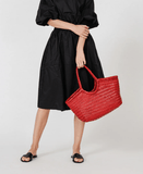 Woman in black dress holding red woven leather tote bag, summer designer handbag