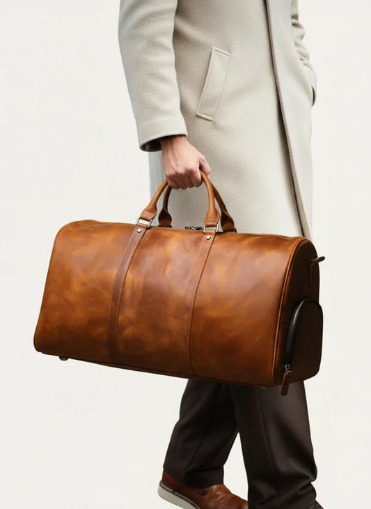 Man holding a large brown full grain leather duffle bag, ideal for travel or gym use