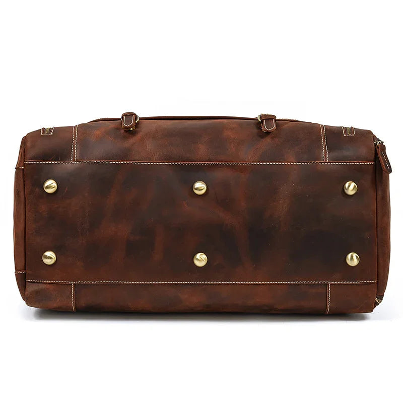 Bottom view of large dark brown full-grain leather duffle bag with metal feet and contrast stitching