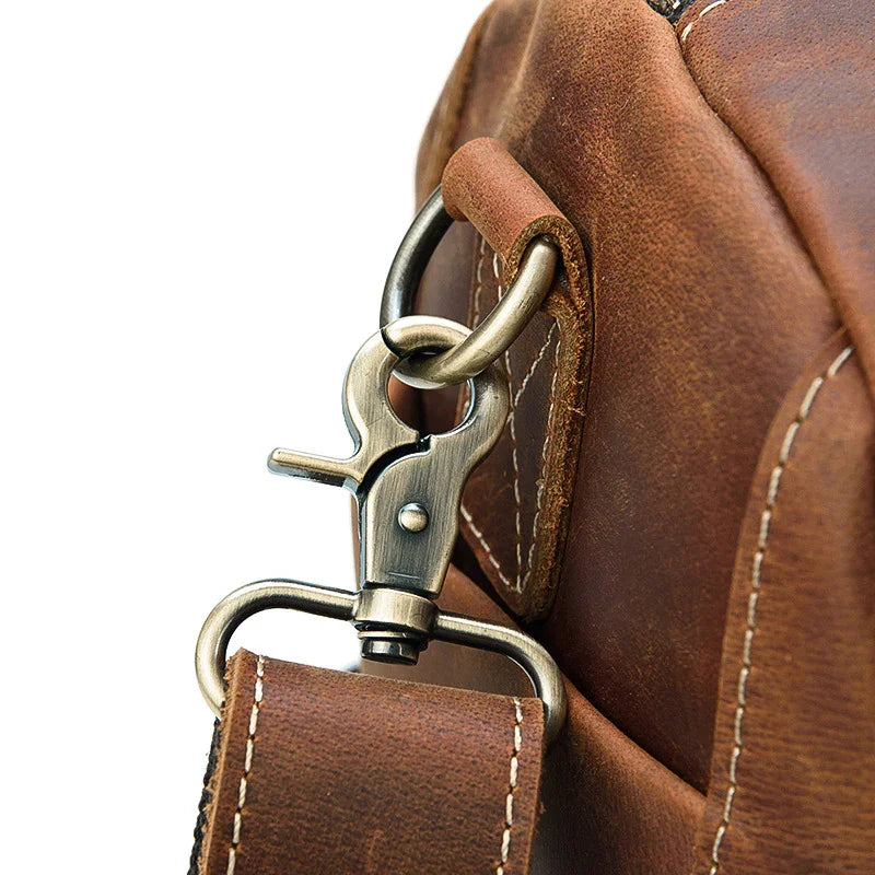 Close-up of brown full grain leather duffle bag with metal clasp and stitched strap