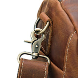 Close-up of brown full grain leather duffle bag with metal clasp and stitched strap