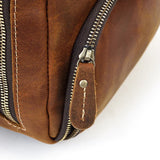 Close-up of a brown full grain leather duffle bag with a metal zipper and stitched pull tab
