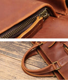 Close-up of handmade full grain leather messenger bag with brass zipper and sturdy handles on wooden surface