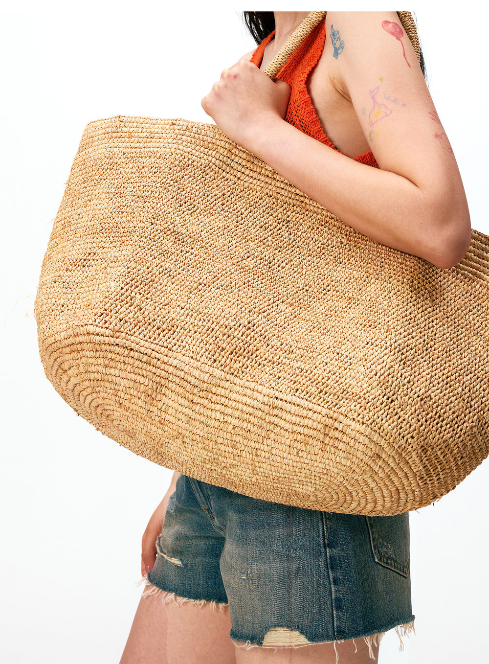 Handwoven raffia tote bag with scarf styling – natural straw beach bag worn with linen dress