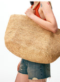 Handwoven raffia tote bag with scarf styling – natural straw beach bag worn with linen dress