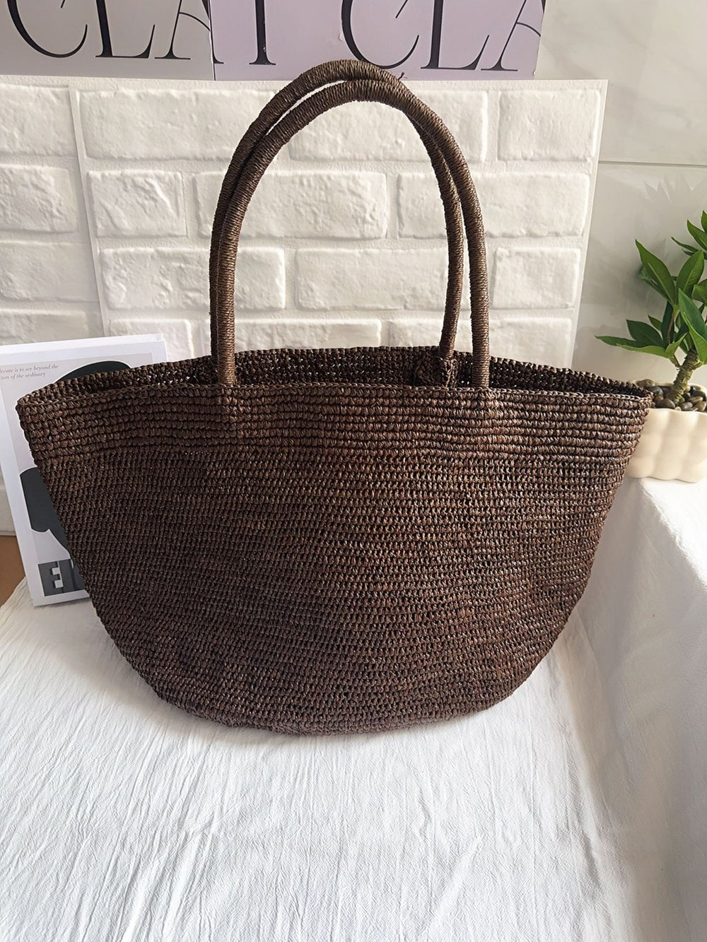 Handwoven raffia straw tote standing upright – structured natural fibre beach bag large size