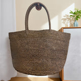 Handwoven raffia tote bag lifestyle – natural straw beach bag worn over shoulder at beach