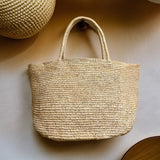 Handwoven raffia tote bag side view – structured woven straw tote with reinforced woven handles