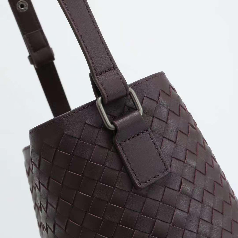 Close-up of a woven dark brown lambskin leather bucket bag with adjustable shoulder strap
