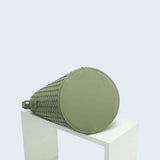 Green woven leather bucket bag with round base, displayed on a white block, modern style