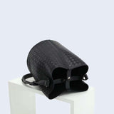 Black woven lambskin leather bucket bag with shoulder strap on white display block