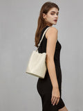 Woman wearing a small woven lambskin leather bucket bag with shoulder strap, crossbody style