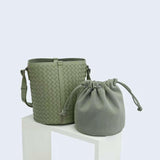Green interwoven lambskin leather bucket bag with matching drawstring pouch on white display