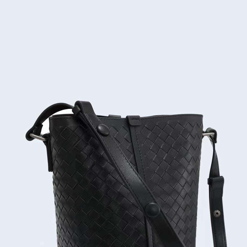 Black woven lambskin leather bucket bag with adjustable shoulder strap and textured pattern