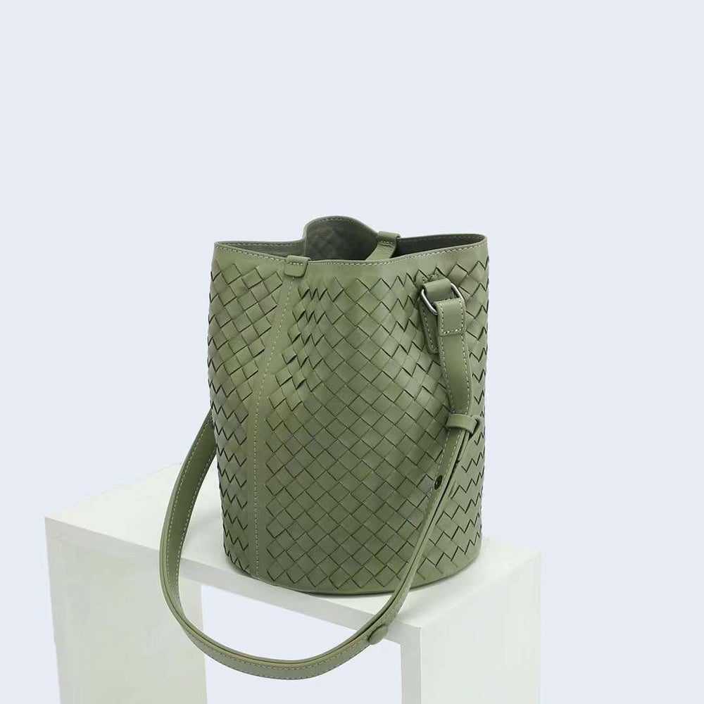Olive green woven leather bucket bag with adjustable shoulder strap on white display.