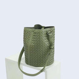 Olive green woven leather bucket bag with adjustable shoulder strap on white display.
