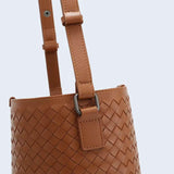 Brown woven lambskin leather bucket bag with adjustable shoulder strap and metal hardware.