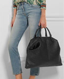 Woman holding large black intrecciato lambskin leather tote bag, quilted weave, stylish look