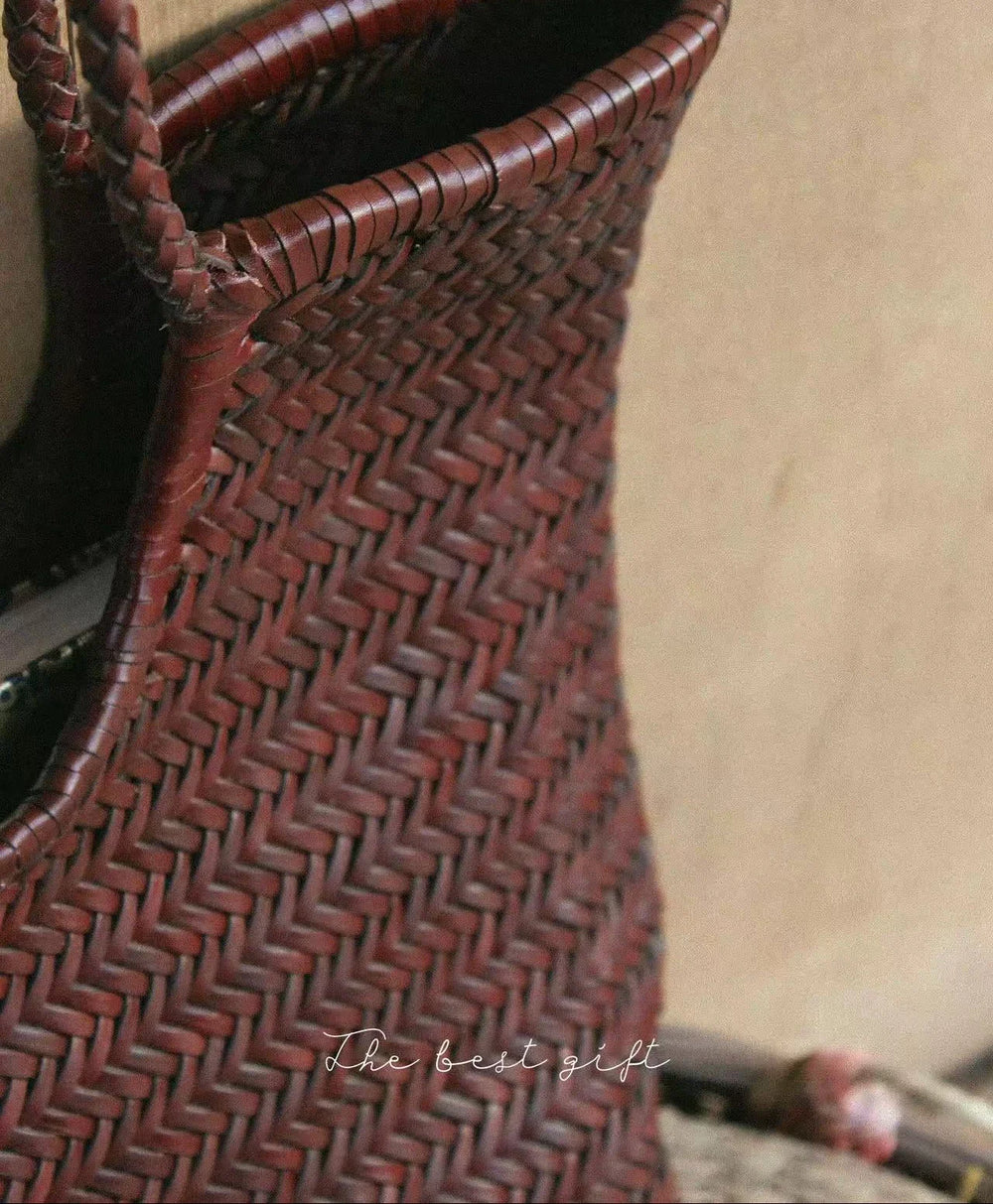 Close-up of a woven brown cowhide leather handbag with bamboo-style handle