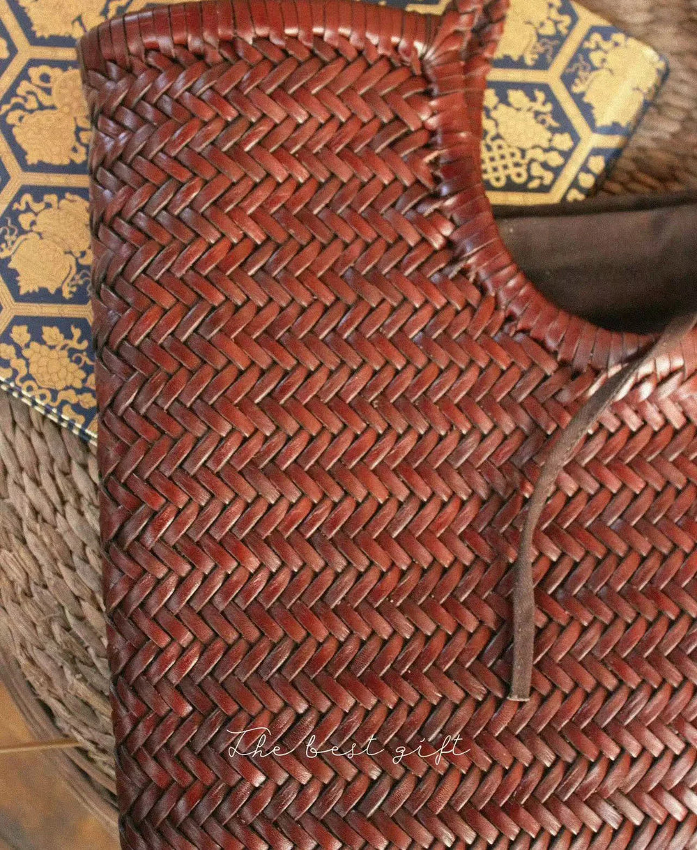 Close-up of a brown woven leather handbag with a herringbone pattern and a rustic cord handle.