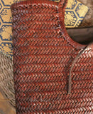 Close-up of a brown woven leather handbag with a herringbone pattern and a rustic cord handle.