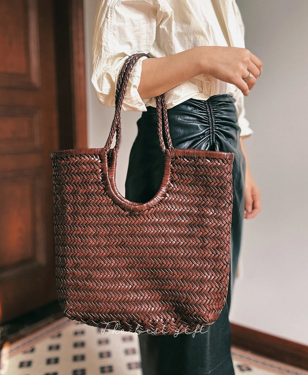 Woman holding brown woven leather tote bag with braided handles, ideal for summer and casual outings
