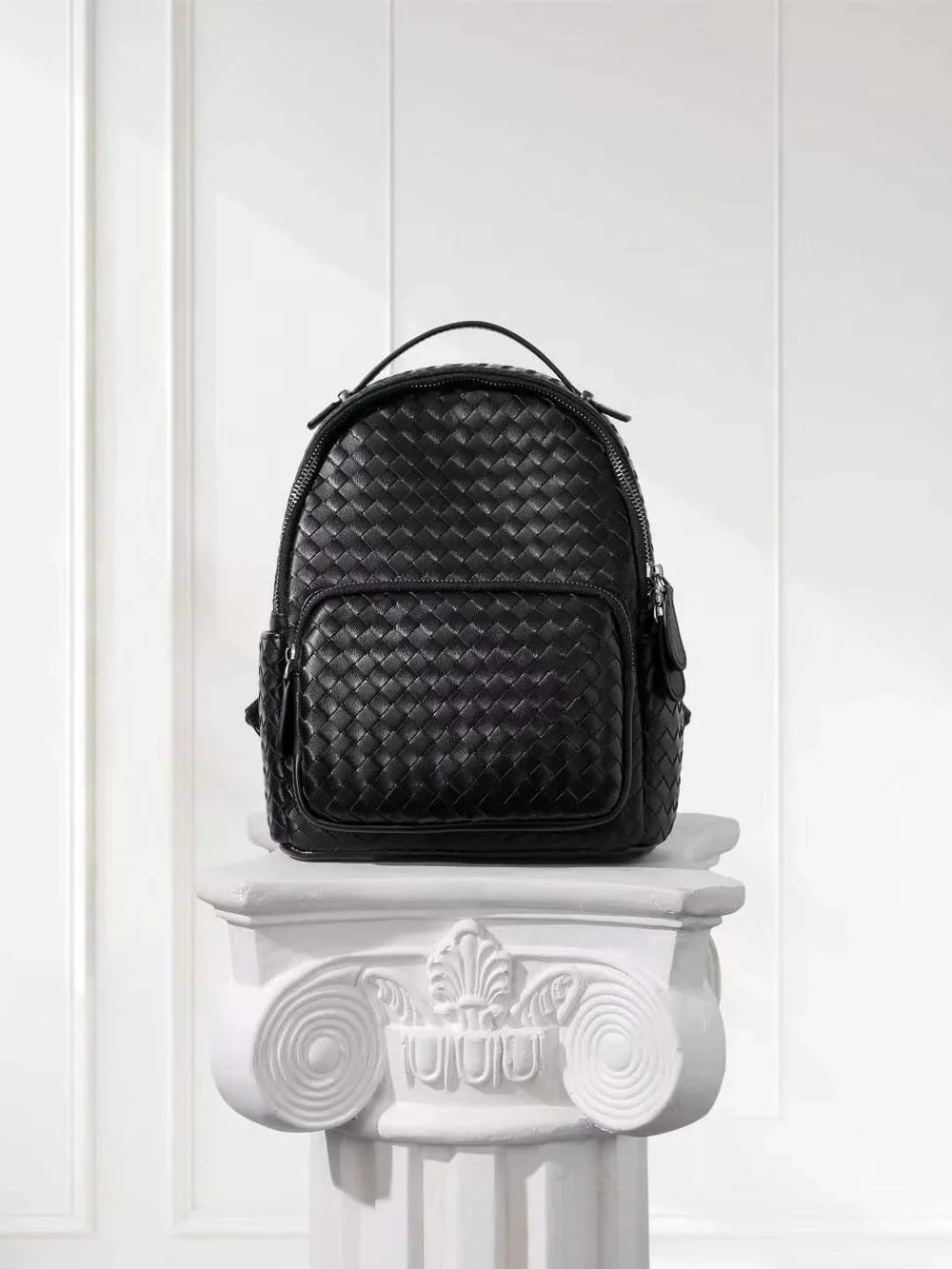 Black woven lambskin leather small backpack with quilted texture on white pedestal