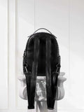 Black woven lambskin leather backpack with adjustable straps on a white pedestal