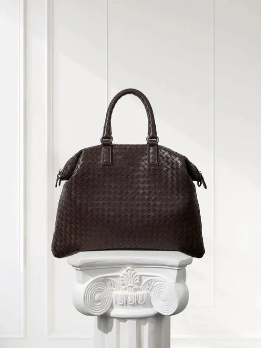 Large black lambskin woven leather tote bag with top handles on a white pedestal