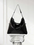 Large black lambskin leather tote with woven intrecciato design on a white pedestal
