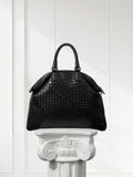 Black intrecciato lambskin leather tote bag with top handles on white pedestal