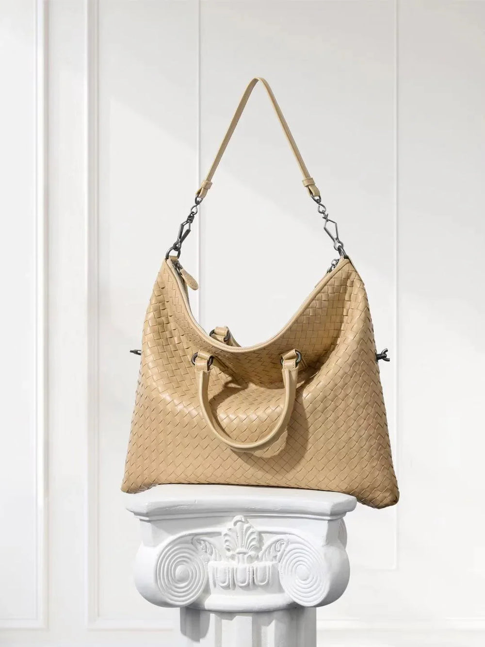 Beige woven lambskin leather tote bag with dual handles on a white decorative pedestal
