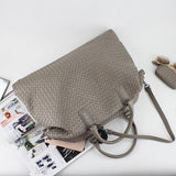 Large taupe woven leather tote bag with handles and detachable strap on a magazine, chic accessory
